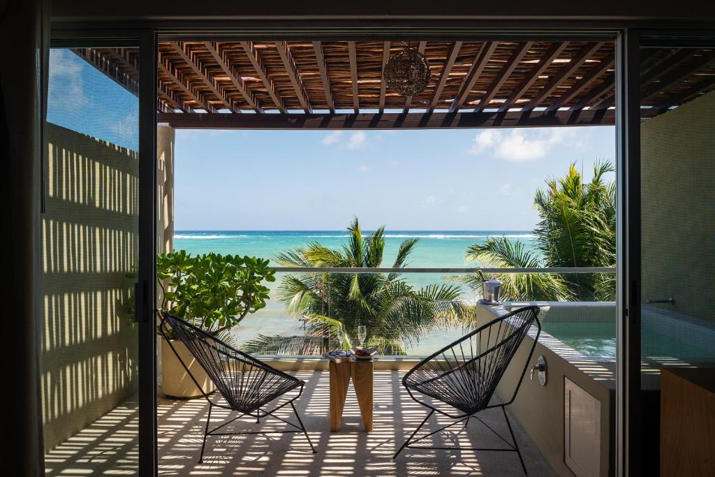 a room with a balcony with a view of the ocean at Mereva Tulum in Tulum