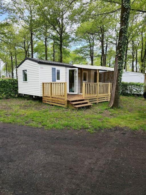 une petite cabine blanche avec une véranda et un arbre dans l'établissement Mobilhome climatisé 3 chambres à 30 min du Puy du F et de Nantes, à La Boissière-de-Montaigu