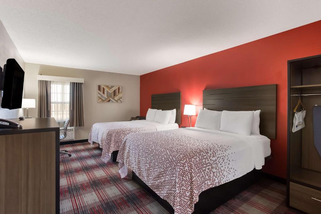 2 bedden in een hotelkamer met rode muren bij SureStay Hotel by Best Western Higginsville in Higginsville