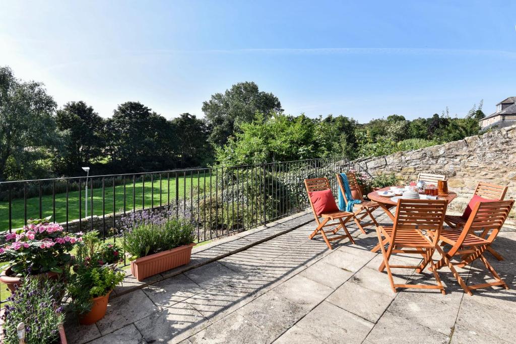 a patio with a table and chairs and a stone wall at Coldstream Coach House in Coldstream