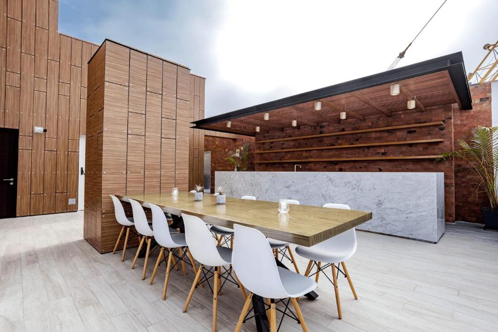 a dining room with a wooden table and white chairs at Pionero by Wynwood House in Lima