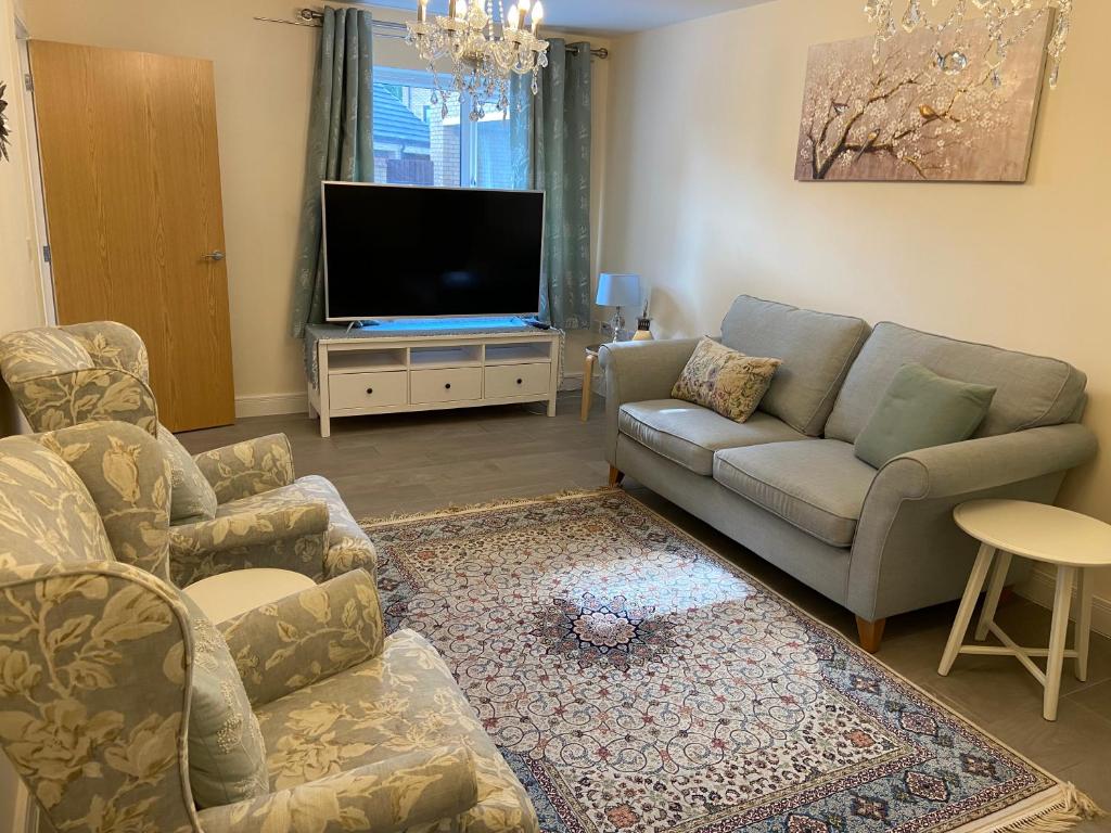 a living room with a couch and a tv at Burton - 4 Bedroom Detached Home in Shenley Church End