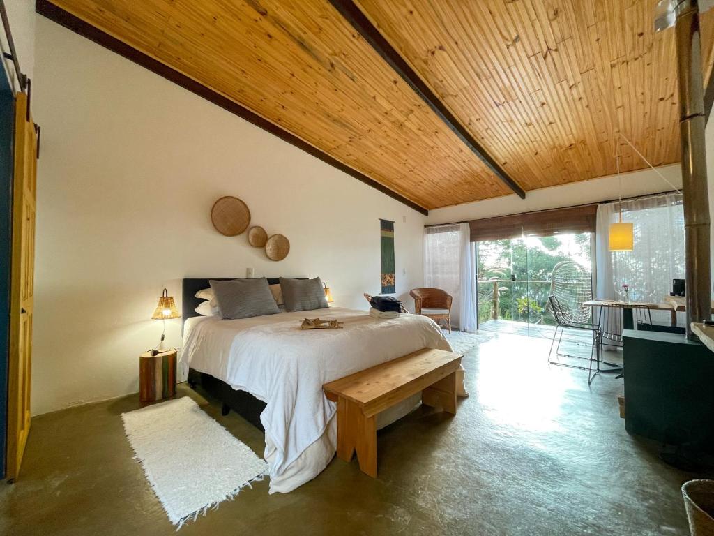 ein Schlafzimmer mit einem großen Bett und einer Holzdecke in der Unterkunft Casa do Galgo in São Bento do Sapucaí