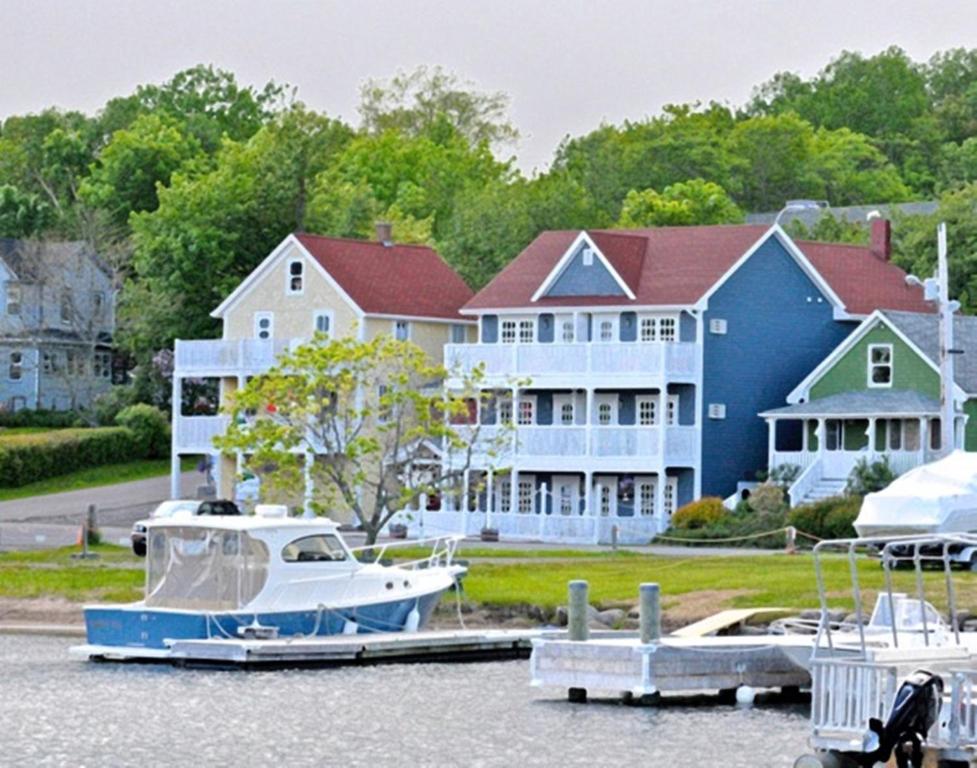 a large house with a boat docked at a marina at The Water's Edge Inn & Gallery in Baddeck