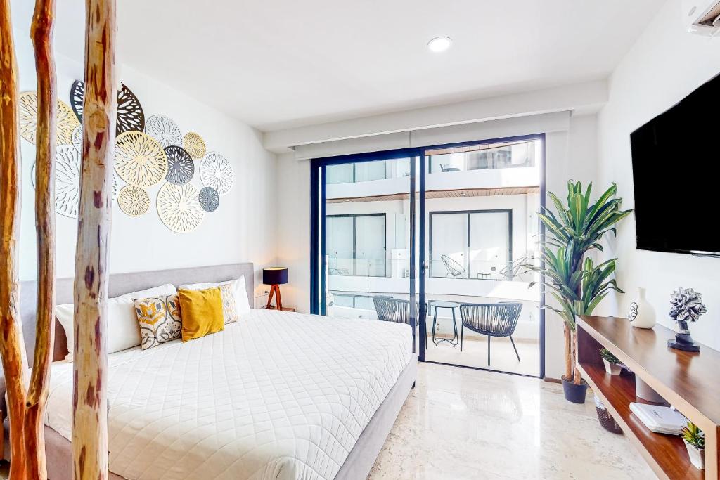 a bedroom with a bed and a large window at Menesse Midtown 2 Unit 208 in Playa del Carmen