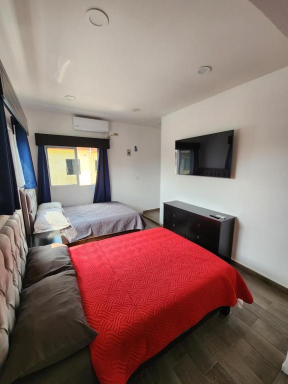 - une chambre avec un lit et un canapé avec une couverture rouge dans l'établissement habitaciones disponibles con baño privado zona centro, à Cunduacán