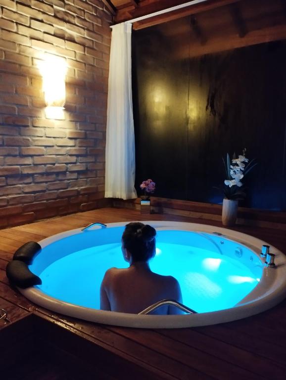 a woman in a jacuzzi tub in a room at Chalé Caminho do Paiol in São Bento do Sapucaí