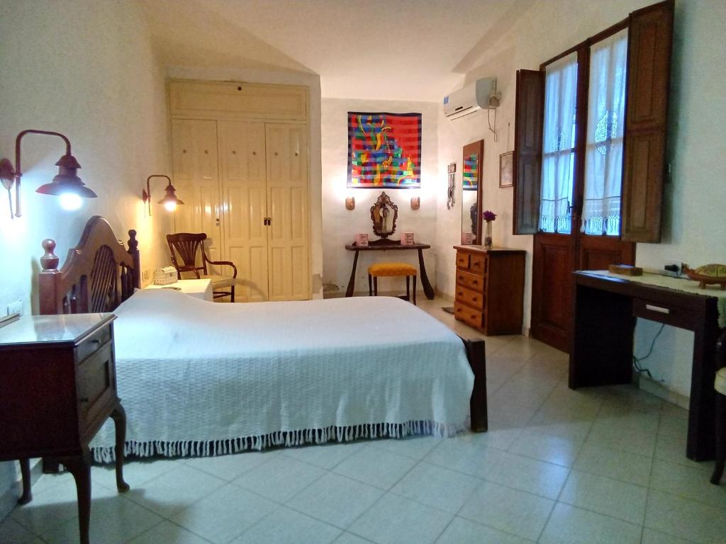 1 dormitorio con 1 cama blanca grande y escritorio en Casa Rústica en Santiago del Estero