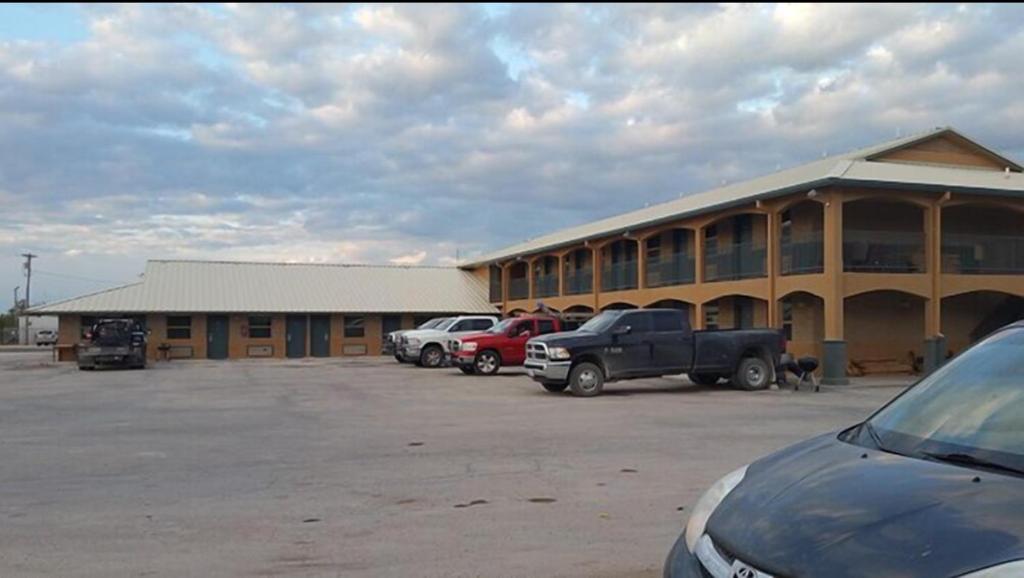 a large building with cars parked in a parking lot at Derrick Inn in Big Lake