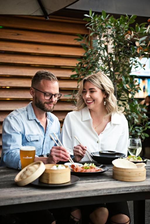 Un hombre y una mujer sentados en una mesa comiendo comida en The Woolpack Hotel, en Mudgee