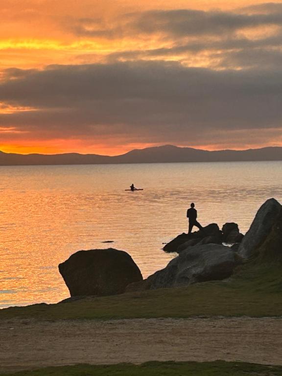 um homem de pé sobre rochas na água ao pôr-do-sol em Wilsons Prom Holiday Park em Yanakie
