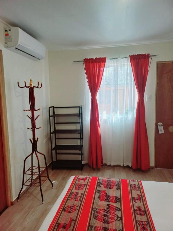 a bedroom with red curtains and a bed with a rug at hostal casa talitha in San Pedro de Atacama