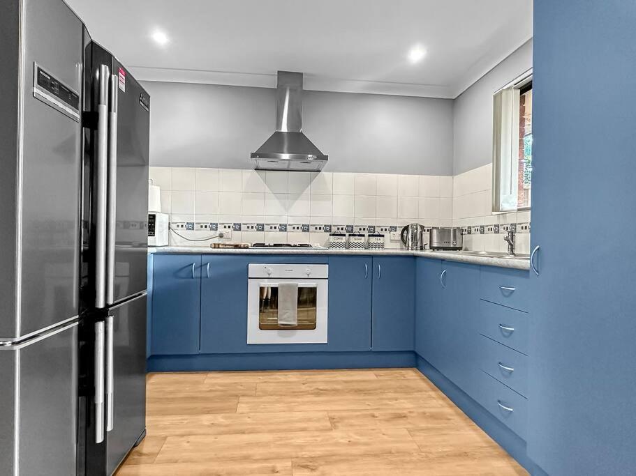 a kitchen with blue cabinets and a black refrigerator at Family Home Close To All Perth Adventures in Hamilton Hill