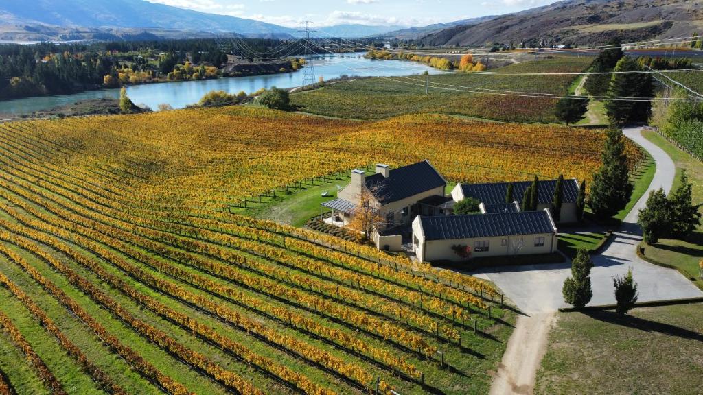 an aerial view of a vineyard with a house and a river at Towan House at Carrick Winery in Cromwell