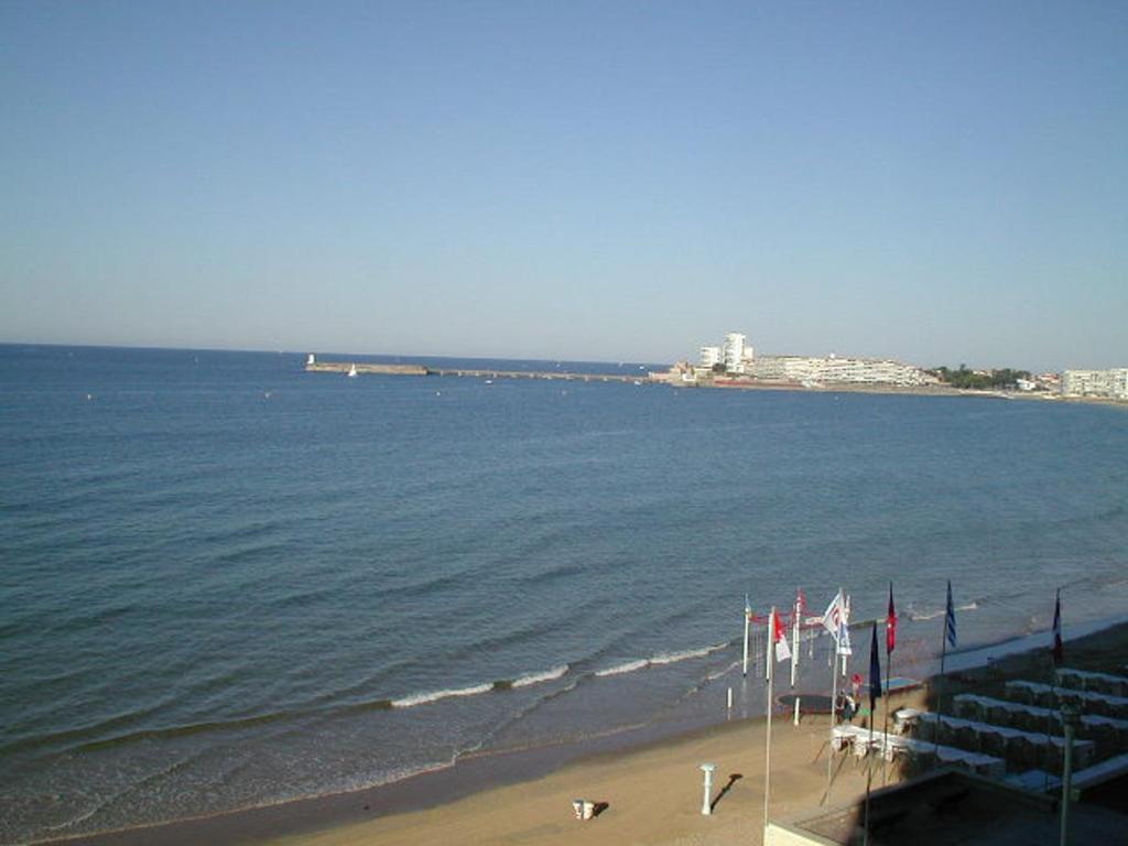 Cette chambre offre une vue sur une plage arborant des drapeaux et l'océan. dans l'établissement Studio tout confort face à la mer avec balcon - Les Sables-d'Olonne - FR-1-331-41, à Les Sables-dʼOlonne