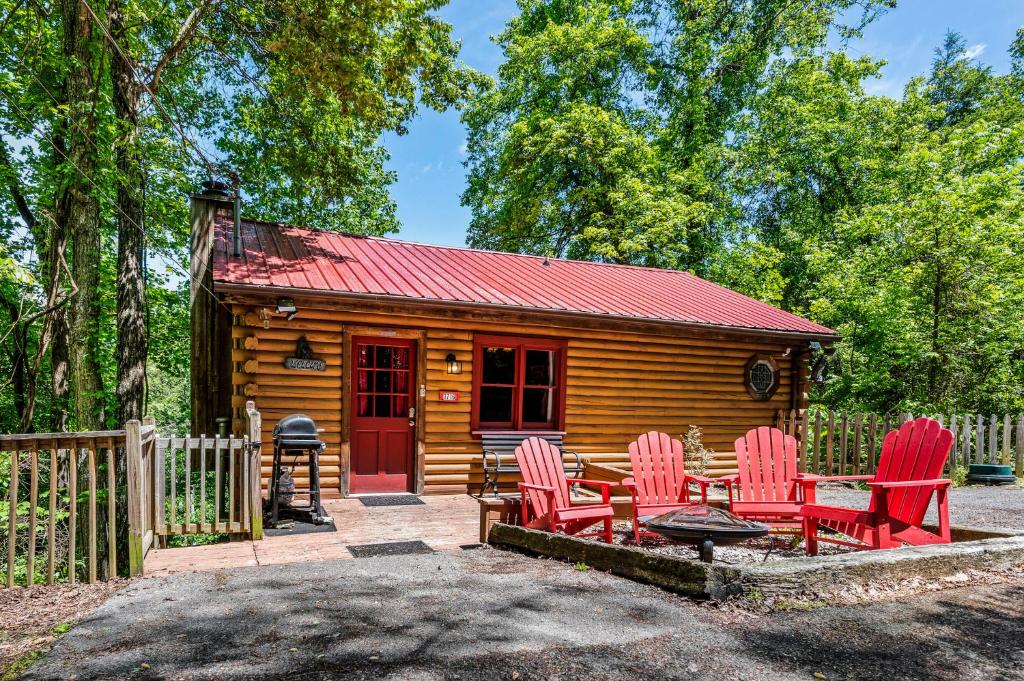 Cabaña de madera con sillas rojas y mesa en Cozy cabin with a mountain view en Pigeon Forge