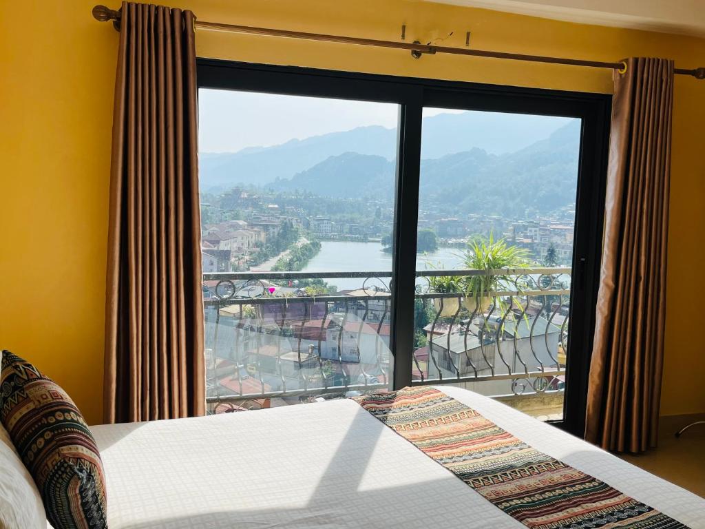 een slaapkamer met een groot raam met uitzicht op een rivier bij Sapa Paramount Hotel in Sa Pa