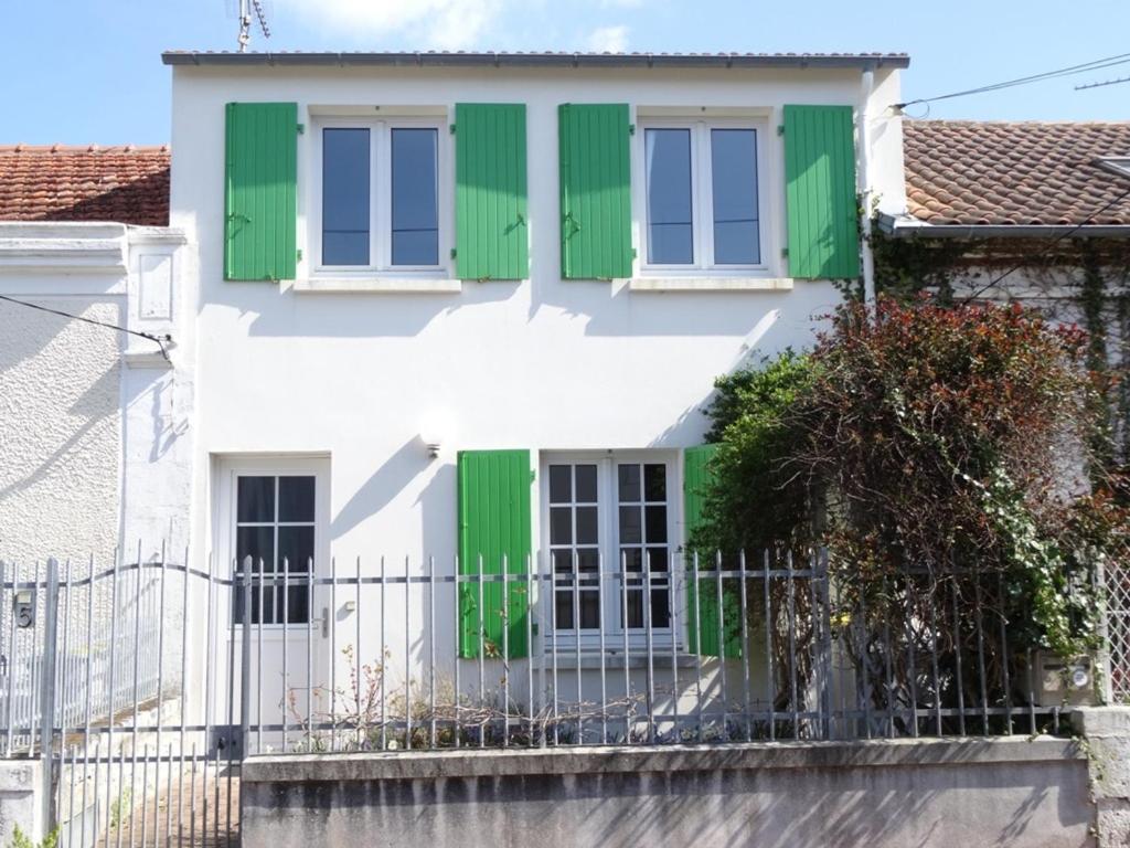 une maison avec des volets verts et une clôture dans l'établissement Maison à Fouras, 3 chambres, cour ombragée, proche centre et plages - FR-1-709-67, à Fouras