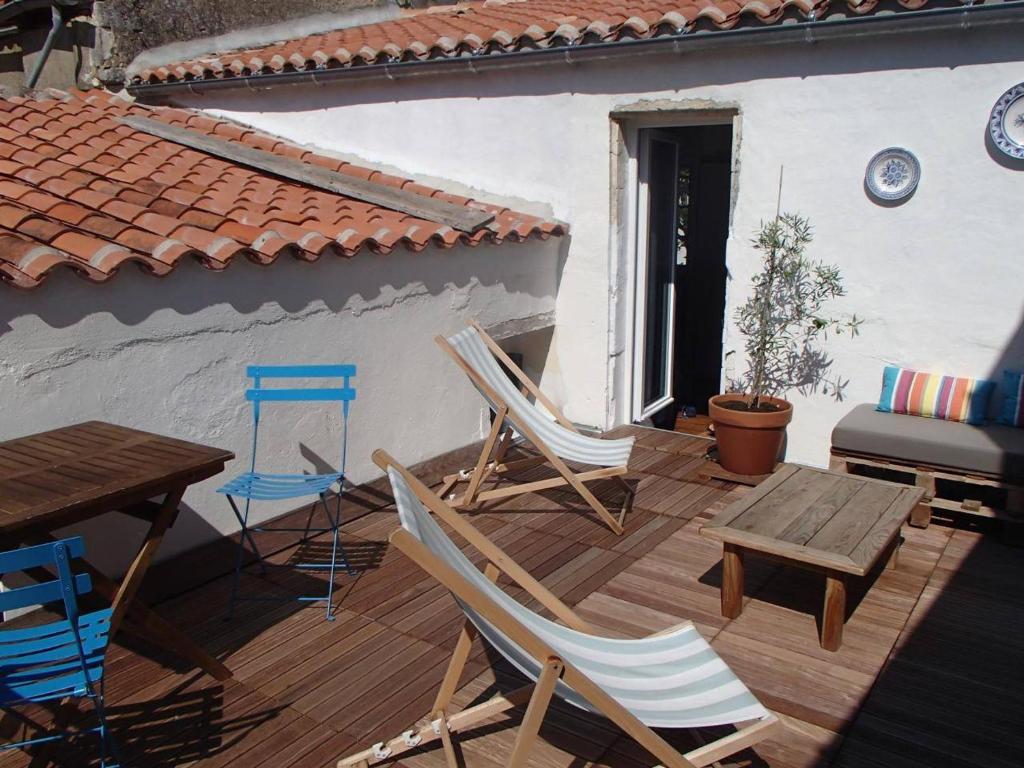 une terrasse en bois avec des chaises, une table et une table dans l'établissement Maison de charme à Saint-Georges-d'Oléron, 8 couchages, proche commerces, cour et terrasse ensoleillée - FR-1-246A-237, à Saint-Georges-dʼOléron
