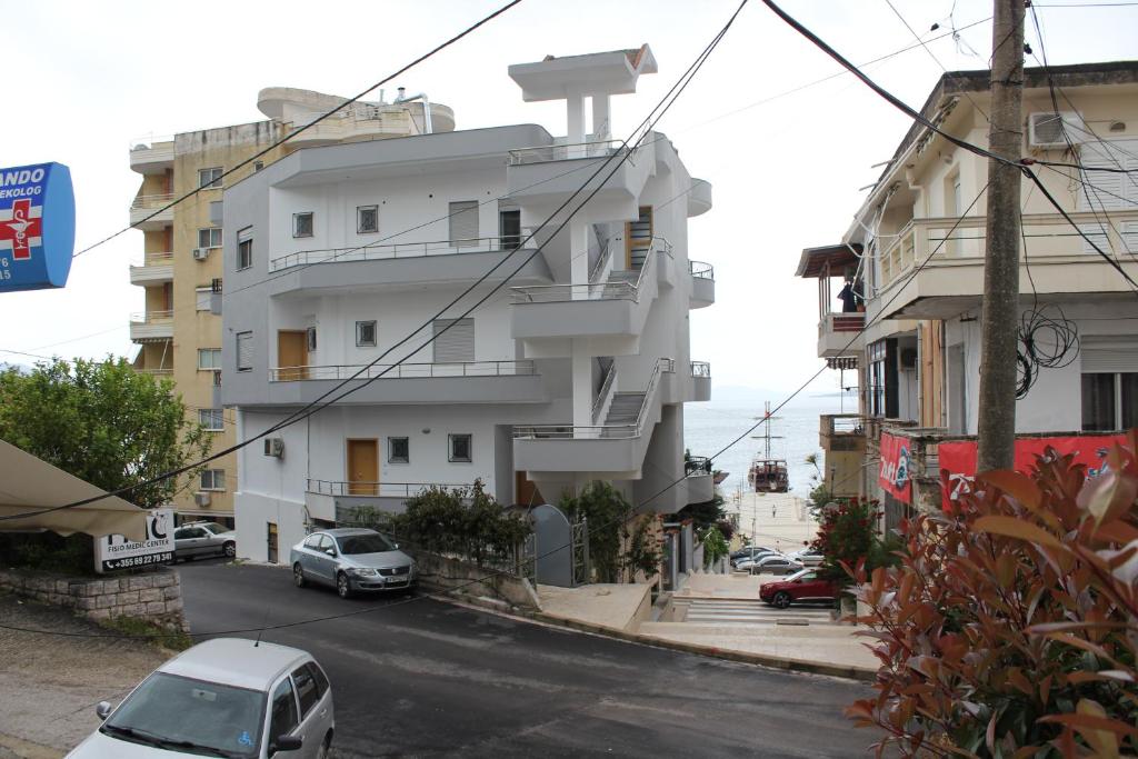 un edificio blanco con coches estacionados frente a él en Margaritas Apartments en Sarandë
