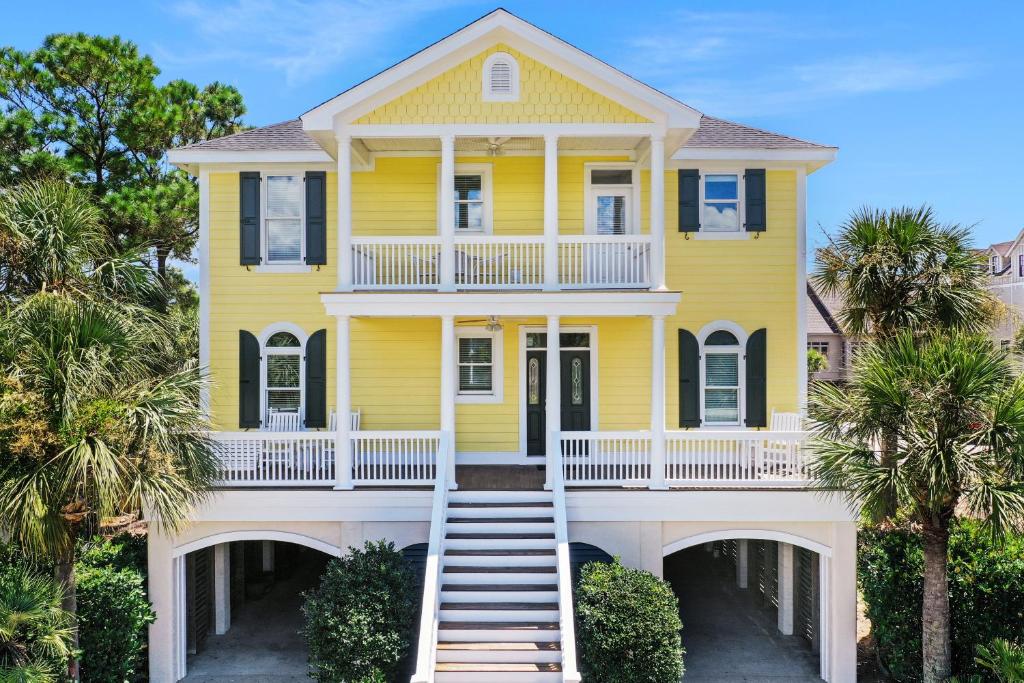 a yellow house with palm trees in front of it at Beach Haven in North Litchfield Beach