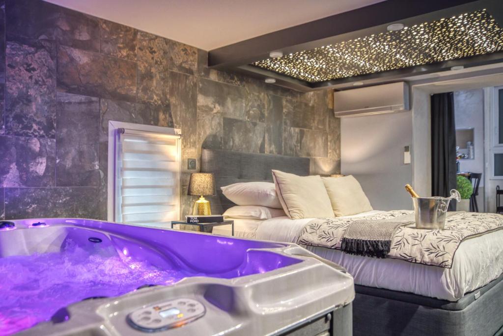 Baño con bañera púrpura junto a la cama en L'Eden Love - Jacuzzi / Sauna, en Grenoble