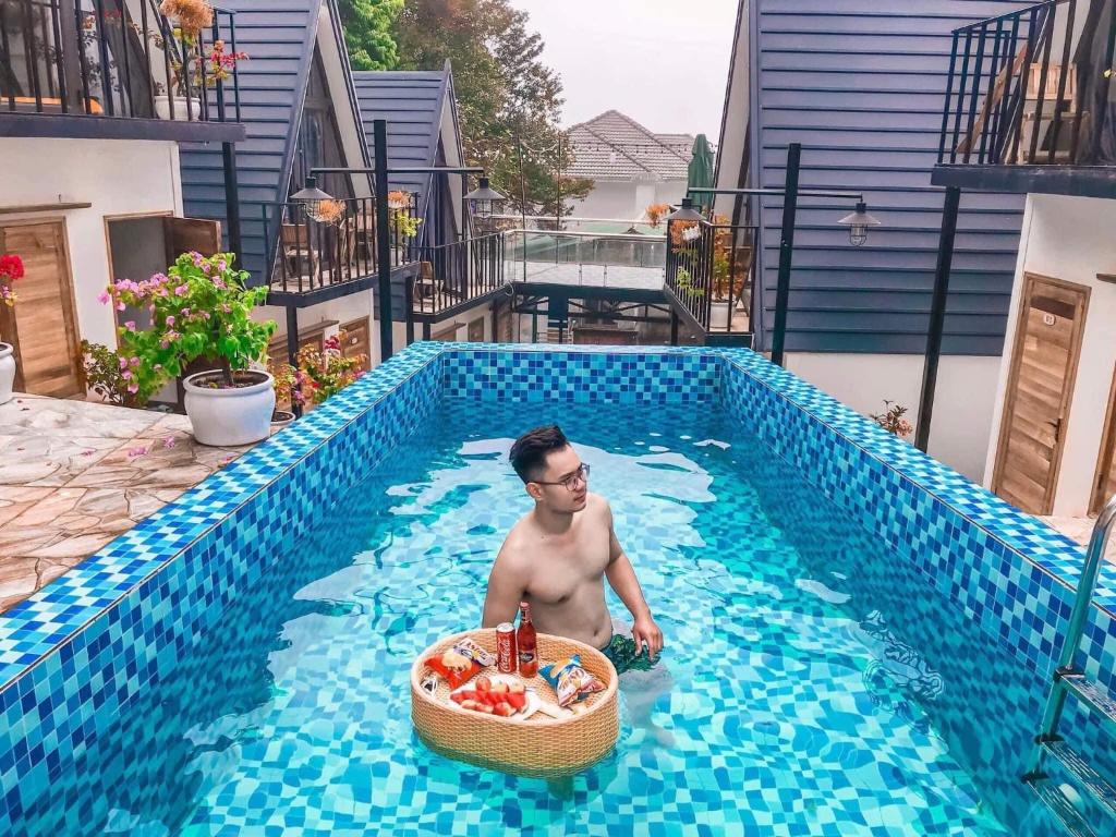 a man in a swimming pool with a basket of fruit at CuDen Homestay Venuestay in Vĩnh Phúc