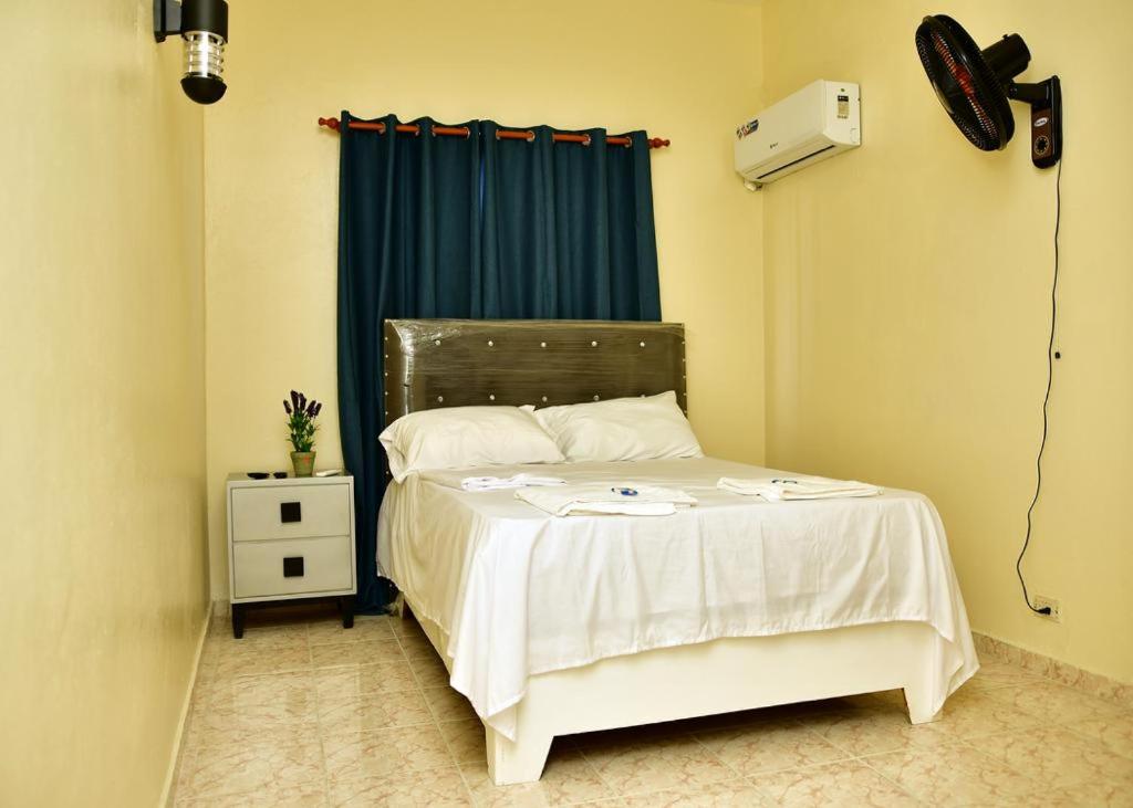a bedroom with a white bed with a fan at Hotel Freedom Nagua in Nagua