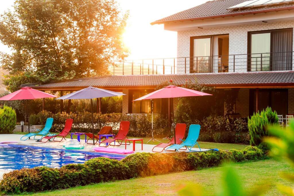 a group of chairs and umbrellas next to a pool at Narya, Peaceful Farmhouse in the Forest in Koycegiz