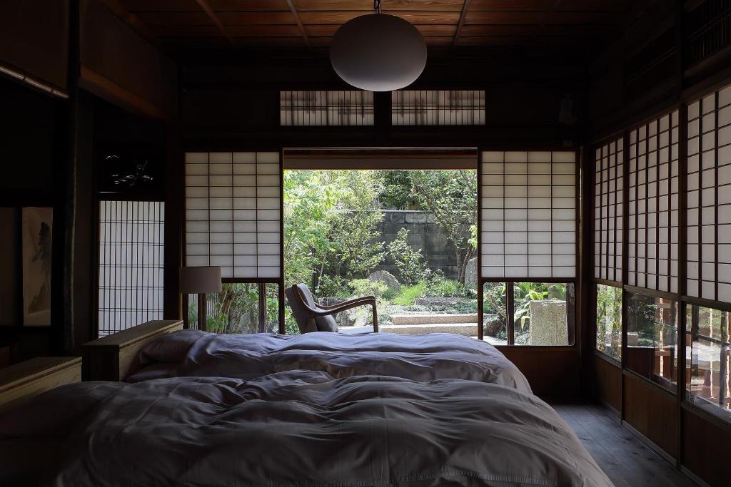 舞鶴市にある古民家の宿宰嘉庵 TraditionalJapaniseHotel Saikaanの窓付きの部屋にベッド付きのベッドルーム1室があります。