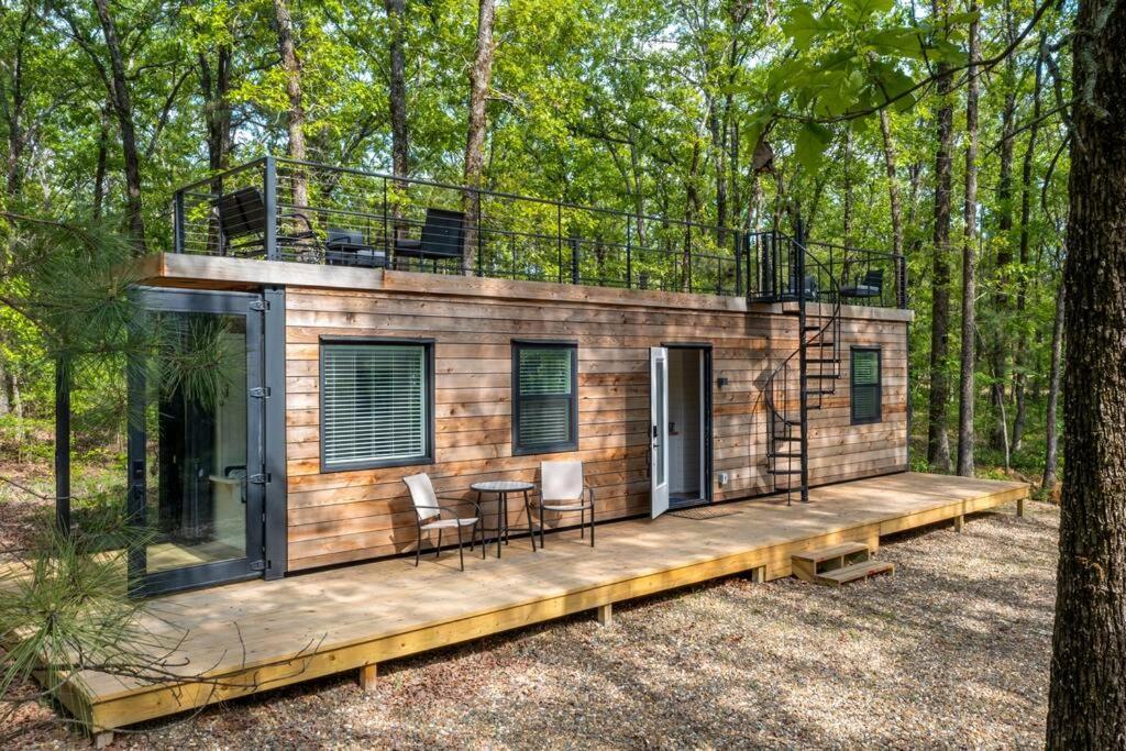 a tiny house in the woods with a deck at Deer Woods in Broken Bow