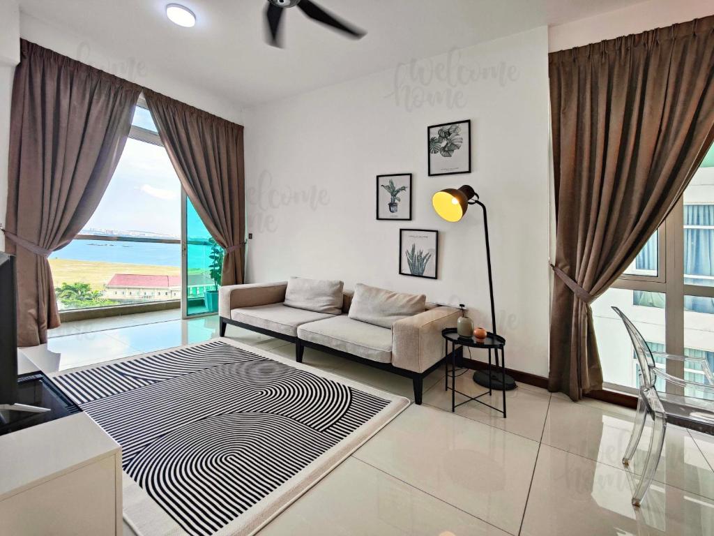a living room with a couch and a large window at Paragon Residences Straits View Homestay by WELCOME HOME in Johor Bahru