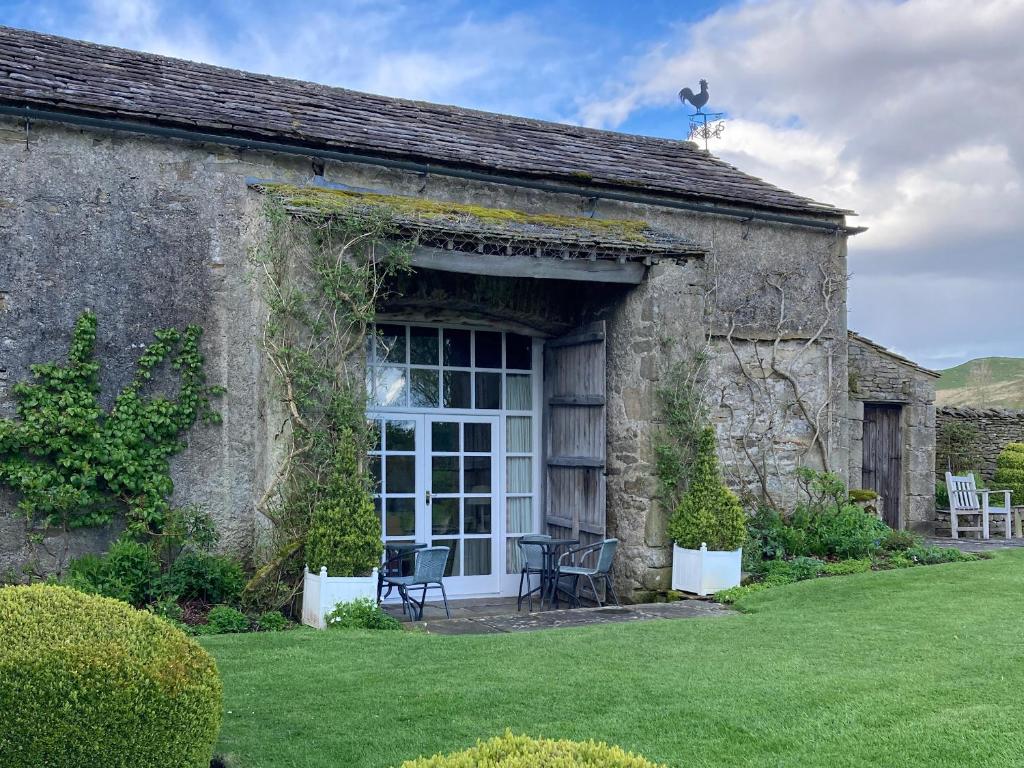 an old stone building with a table and chairs outside at The Garden Rooms Lawkland in Austwick