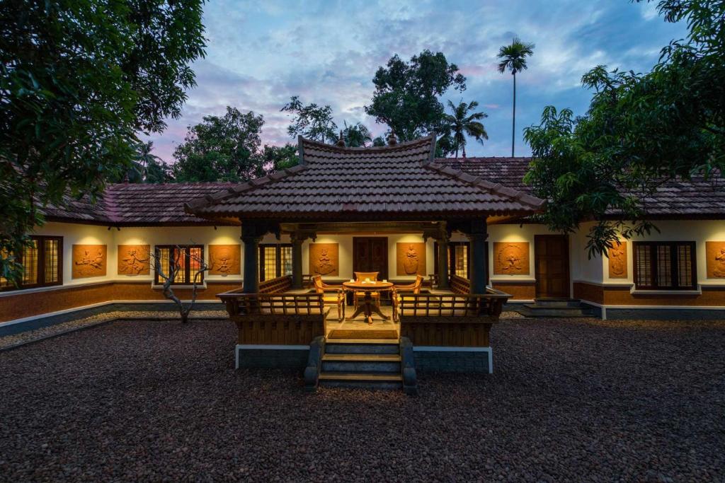 a building with a table and chairs in front of it at The Backwater Heritage- Comp Breakfast with River View & Lawn by StayVista in Alleppey