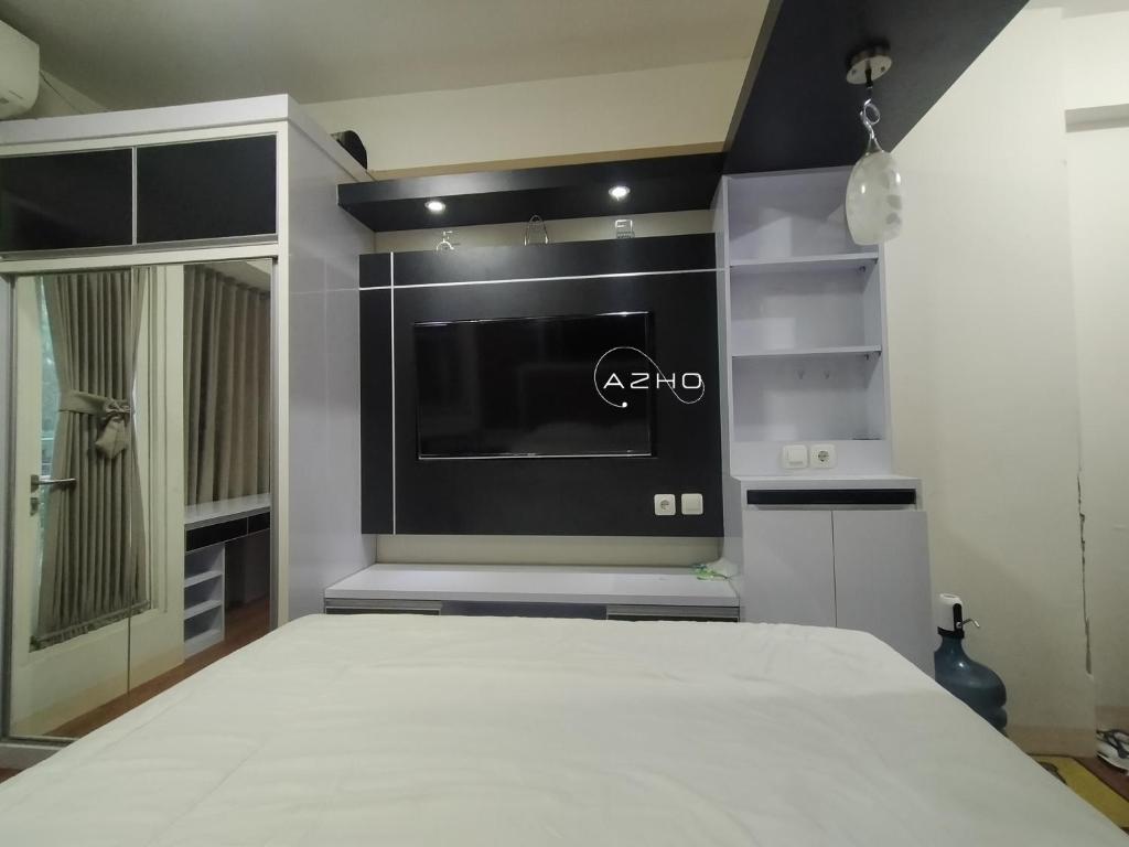 1 dormitorio con TV de pantalla plana grande en la pared en Airin Suite en Depok