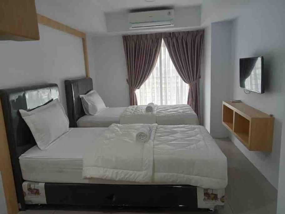 a hotel room with two beds and a window at Studio unit Deprima Apartemen in Medan