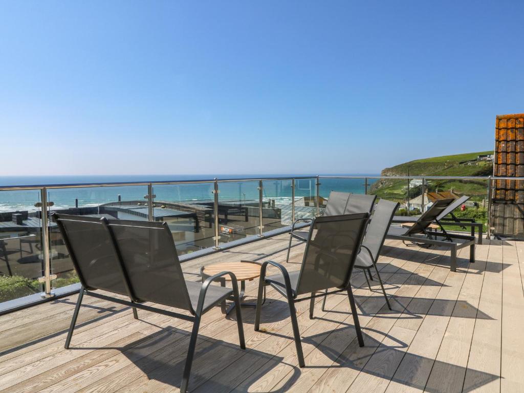 a row of chairs sitting on a deck overlooking the ocean at Trelawns in Mawgan Porth