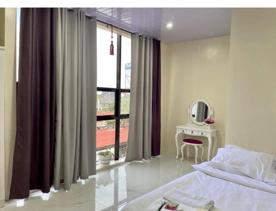 a bedroom with a bed and a mirror and a window at Quirino Hub Charming hotel 1 BR in Davao City