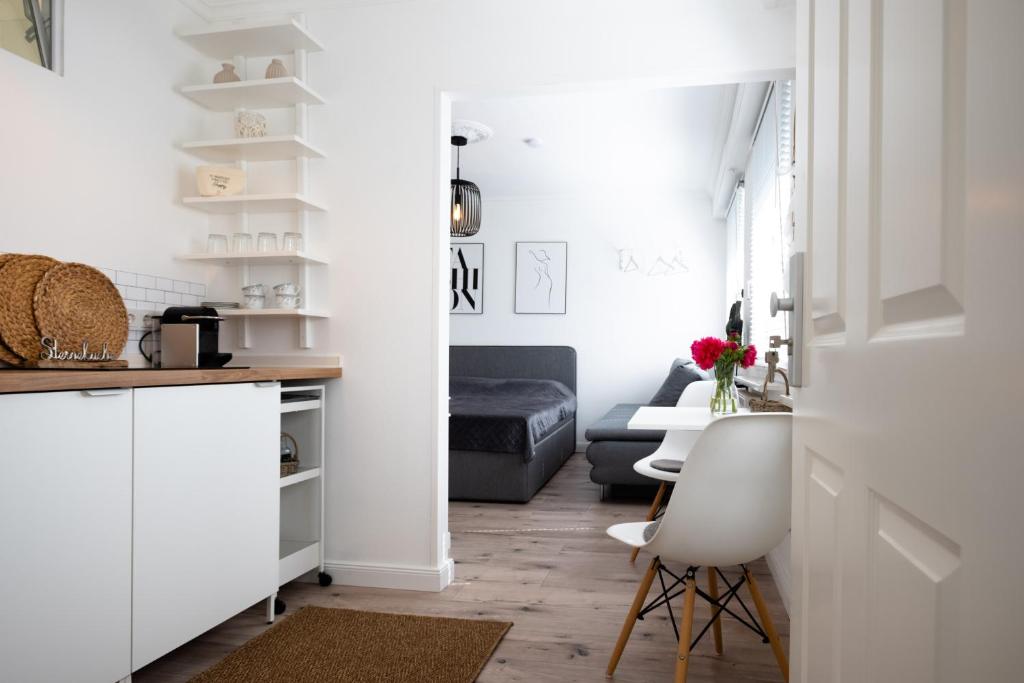 uma cozinha com armários brancos e uma sala de estar em Köhlz Appartment & Restaurant im 1. OG 