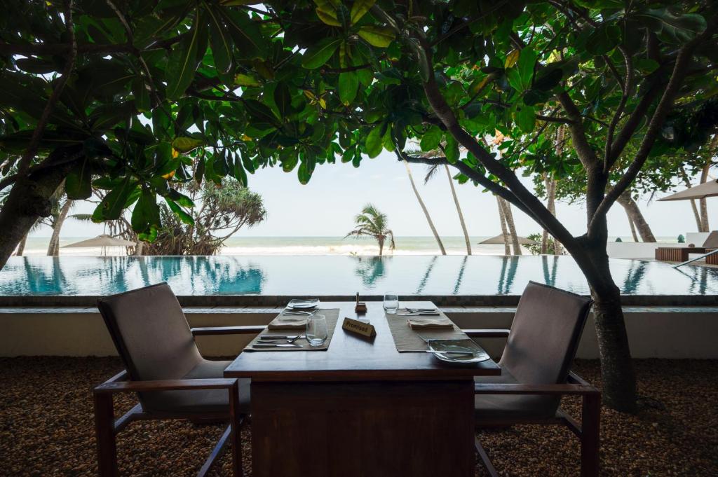 a table and chairs with a view of a pool at Riff Hikkaduwa in Hikkaduwa