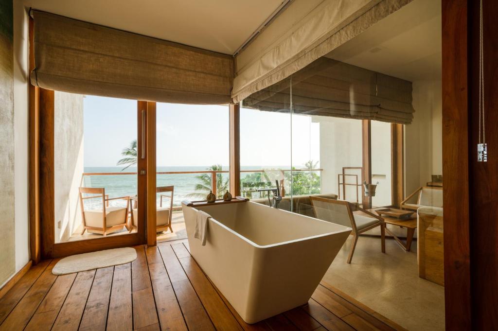 a bathroom with a tub and a view of the ocean at Riff Hikkaduwa in Hikkaduwa