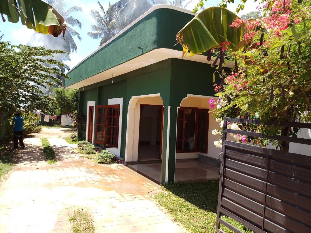 un edificio verde y blanco con una valla en Inn On The Bay Home en Kalkudah