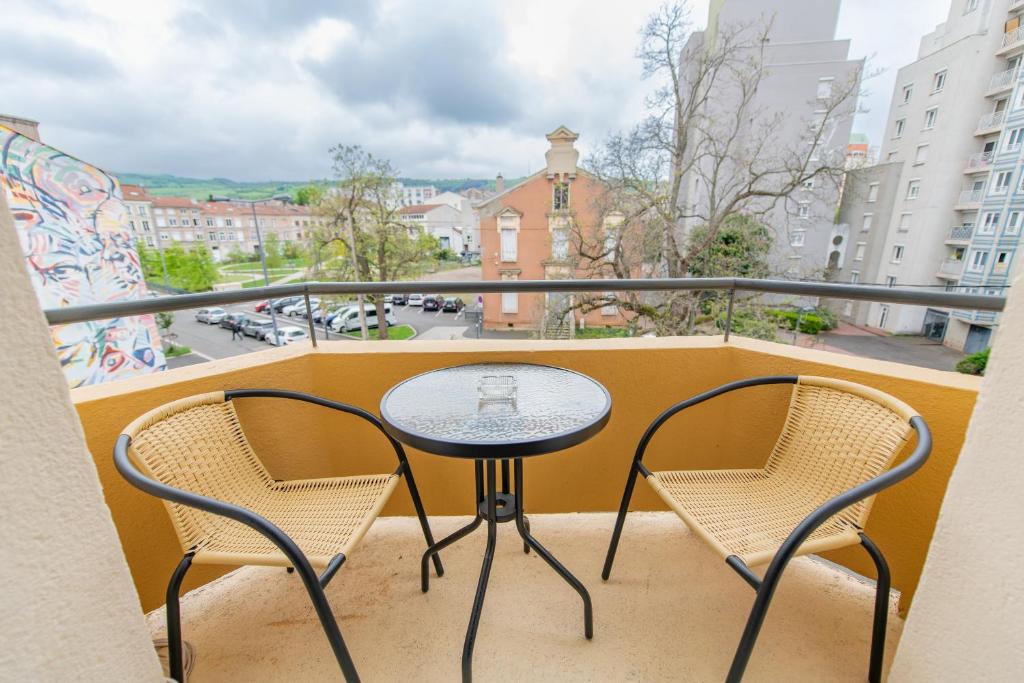 uma mesa e cadeiras numa varanda com vista para a cidade em KASA Cocon - Entièrement équipé avec Balcon em Saint-Étienne