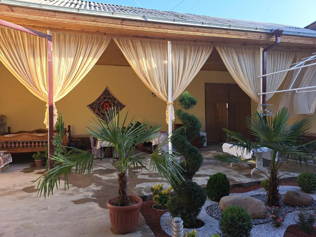 a patio with curtains and plants in a house at Royal lux Guest House in Samarkand