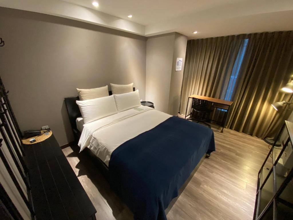 um quarto com uma cama grande e um cobertor azul em Yomi Hotel - ShuangLian MRT em Taipei