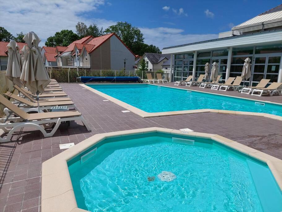 une grande piscine avec des chaises et un bâtiment dans l'établissement Maison 3 piscines - Résidence 3 étoiles, à Pornichet