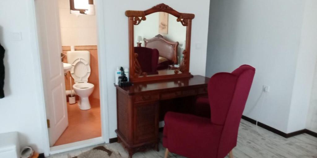 a bathroom with a mirror and a red chair at хотел Кристиан in Sozopol