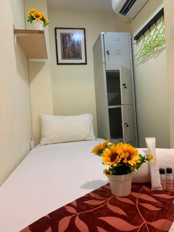 a bedroom with a white bed with a vase of flowers at Sandpiper Hotel Single Room, Long Stay and Short Hours in Singapore