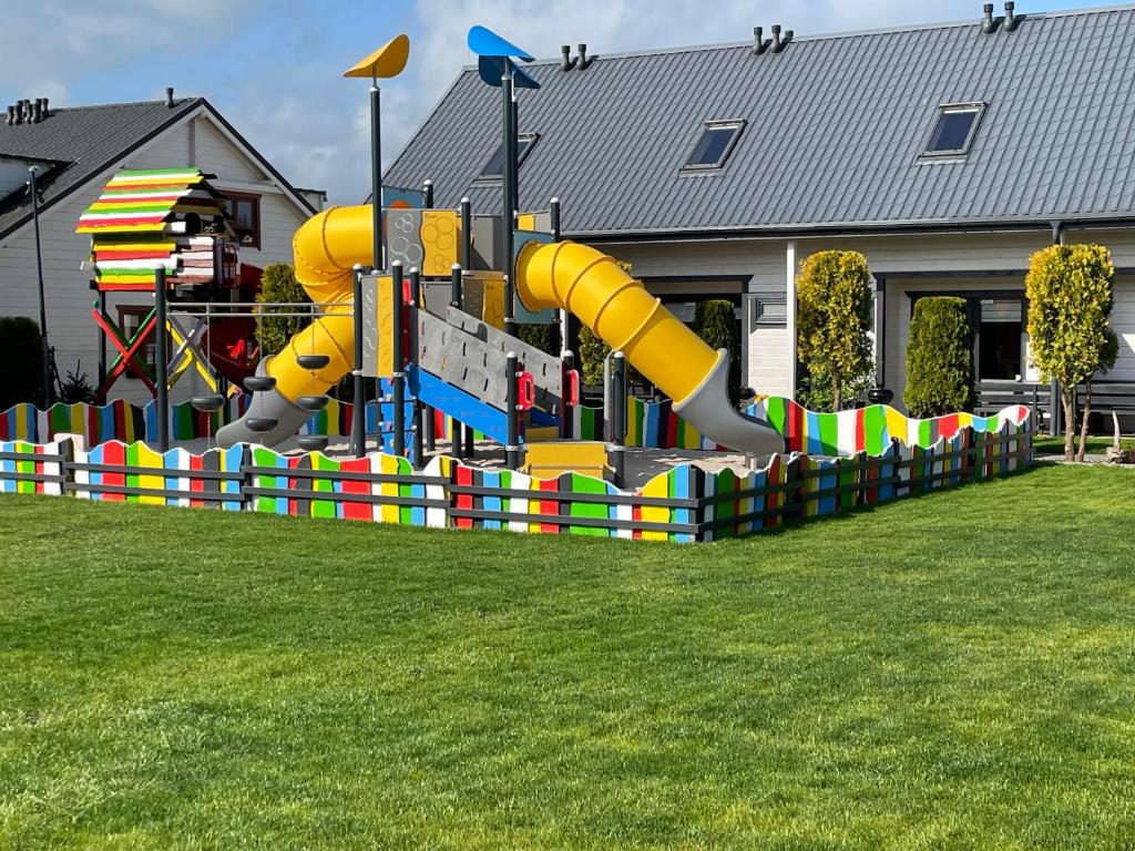 a playground with a slide in a yard at Amelia Domki in Sianozety