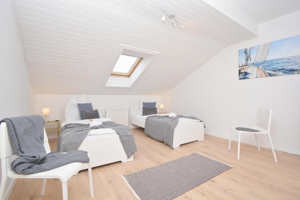 ein weißes Zimmer mit 2 Betten und einem Stuhl in der Unterkunft ERH02-FW Apartment in Herzogenaurach in Herzogenaurach